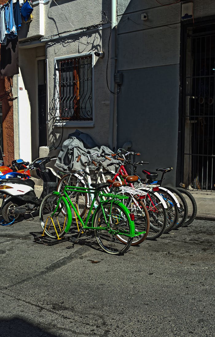 about-us-01 A row of colorful bicycles parked on a sunny city street beside urban architecture.